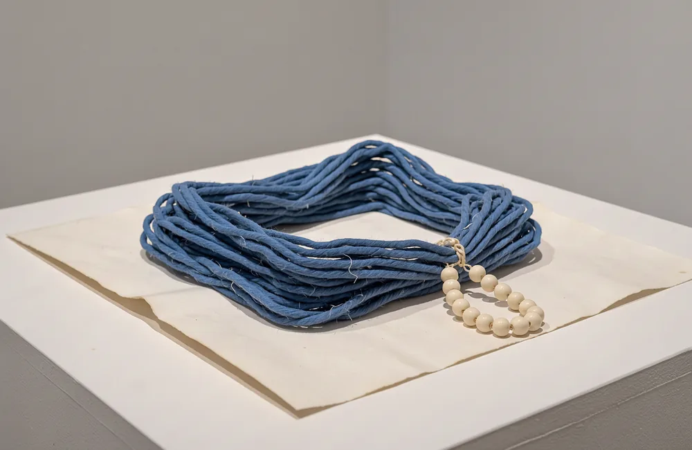 A large folded blue cord model with a small cream chain attached